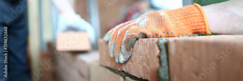 Fotomural Close-up of careful man laying red bricks on well made masonry