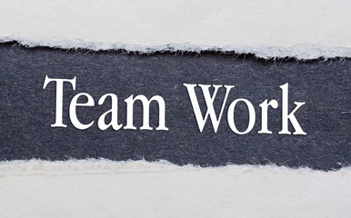 Team Work words under torn black paper.