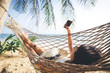 © Peera - Happy woman with mobile phone relax in hammock