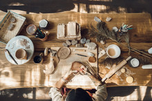 Craftsperson Concept. Young Woman Making Pottery Indoors Sitting Using Modeling Tool To Create Pattern On Cup Top View Workplace