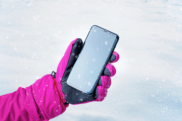 Poster - Phone in girl hand. Cold weather with snowflakes and frost on the phone. Concept of using a mobile phone in cold weather with reduced battery life