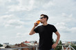 © mirage_studio - Happy man in black shirt and eyewear drinking beer at bar or pub on roof, copy space
