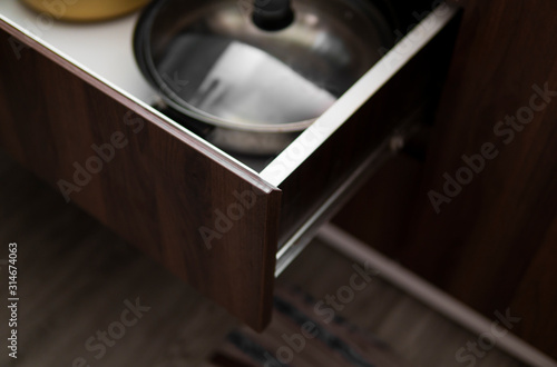 Fotomural Metal chromed pots in a drawer in a modern kitchen.