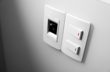 White switch on a white wall with two switches and one common switch.