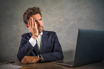 depressed and stressed attractive hispanic businessman in suit and tie working  exhausted at office computer desk frustrated and overworked as executive man in trouble