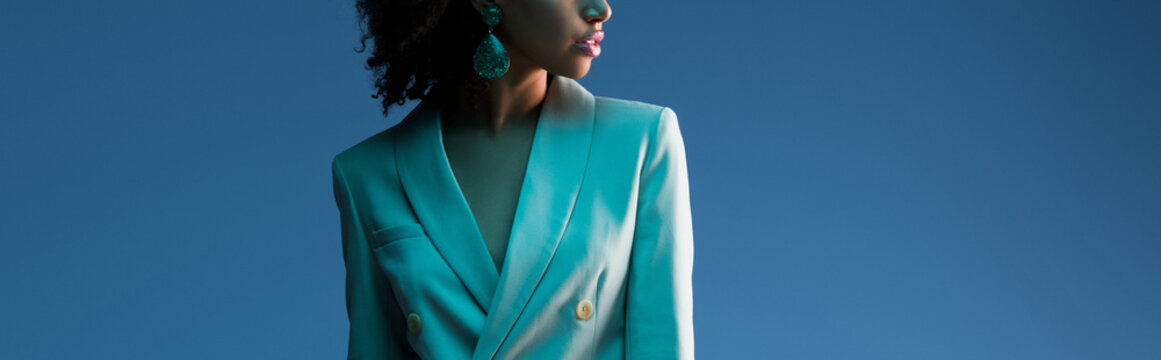 panoramic shot of african american woman in suit isolated on blue