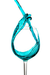 glass with pouring blue drink on a white background with splashes