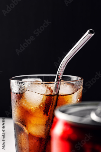 Glass glass with soda and ice ,metal reusable straw for cocktails,can on foreground