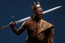 African Man In A Crown And Cloak Holds A Sword In His Hand.