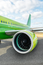 Vertical Photo Of Green Modern Civil Passenger Aircraft On Airfield. On The Foreground A Close-up Of The Airplane Engine And Wing. Blades Of Jet Turbine. Traveling Concept. Copy Space.