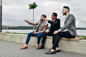 Wall Mural - Three business people discussing, cogitation outside the office.