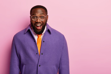 studio shot of handsome cheerful man in bright formal clothes, stands self assured, has happy reacti