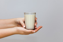 A Glass Of Milk In A Woman's Hands On A White Background