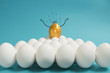 Business recruitment, talent management. One golden egg with crown in top of white eggs group on blue background.