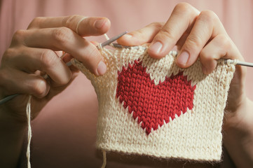 Wall Mural - Concept of love and concern. Woman knitting the red heart for her loved one. Valentines postcard.