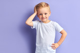 Honey little boy posing isolated over purple background, looking at camera. Portrait