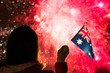 © flowertiare - Fireworks at night. Woman in winter clothes with Australian flag on the New Year.