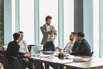 business coworking of young caucasian bearded men in office gathered to discuss business ideas, share experiences and opinions, successful cooperation of enthusiastic business people