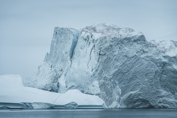 Arctic nature landscape with icebergs in Greenland icefjord with midnight sun sunset sunrise in the horizon. Early morning summer alpenglow during midnight season. Ilulissat, West Greenland.