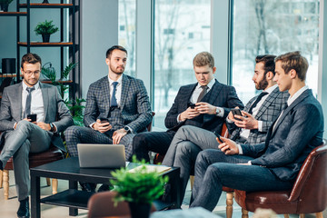 group of young business men gathered together to discuss business strategies and new ideas, business coworking in modern executive boardroom, everyone in stylish elegant tuxedo