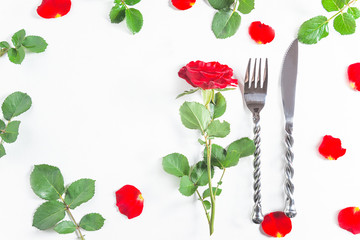 Wall Mural - Romantic table setting for Valentine's day dinner. Beautiful cutlery, one red rose and petals on white background. Space for text