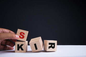 Financial risk assessment, risk reward and portfolio risk management concept. Four wood cubes stacked with  letters R, I, S, K on cubes. Hand trying to move a cube. Copy space.