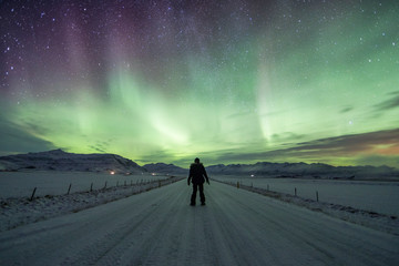 Wall Mural - Northern Lights (Aurora Borealis) above a solo traveller on the road