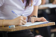 © panitan - high school,university student study.hands holding pencil writing paper answer sheet.sitting lecture chair taking final exam attending in examination classroom.concept scholarship for education abroad