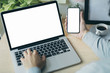 © panitan - mockup image blank screen computer,cell phone with white background for advertising text,hand woman using laptop texting mobile contact business search information on desk in office.marketing,design