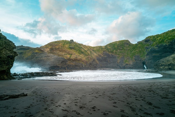 Wall Mural - Wide angle view of Piha Gap and tidal lagoon with Camel Rock island in background