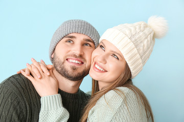 Wall Mural - Portrait of happy couple in winter clothes on color background