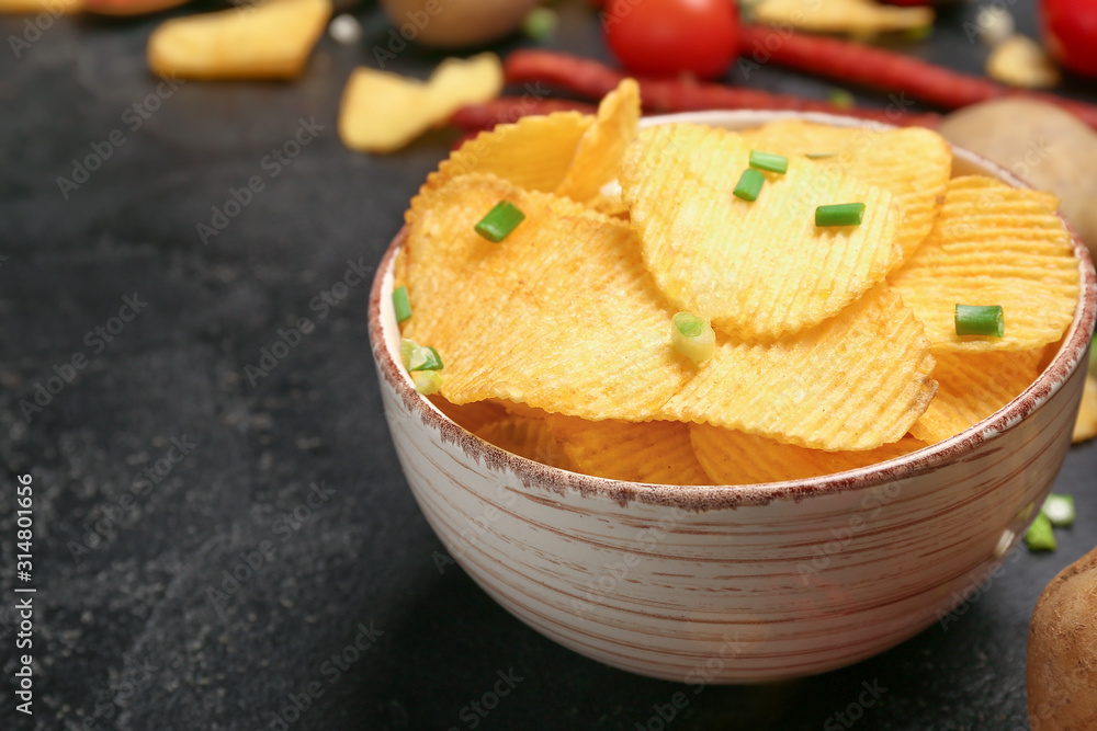 Bowl with tasty potato chips on table