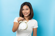 © suriya - Portrait of confused asian young girl holding alarm clock isolated on blue background