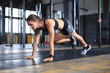 © ty - Portrait of a muscular woman doing planks on gym floor.