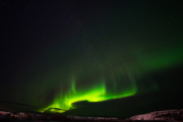 hills, clear starry sky and colorful northern lights, an incredible natural phenomenon