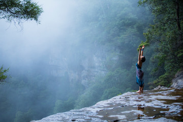 Young beautiful female doing yoga pose above Blue Mountains, Sydney Australia
