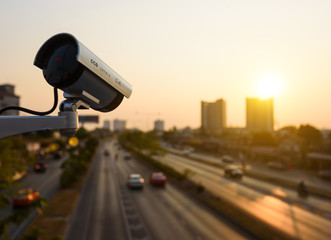 CCTV, Surveillance camera operating in city watching traffic road at sunset