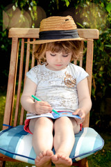 Wall Mural - cute little girl doing homework in the garden