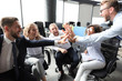 © ty - Happy young people sitting in office and giving high five to their colleagues.