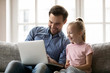 © fizkes - Young dad and little daughter have fun using laptop