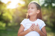 © Khorzhevska - Little girl looking up to at sky with hands on chest, summer nature outdoor. Happy smiling kid feels grateful, wishes dream come true