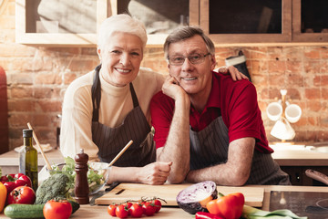 Cheerful senior couple posing at kitchen interior