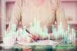 © peshkova - Hand taking notes in notepad. Forex chart holograms in front. Concept of research. Double exposure