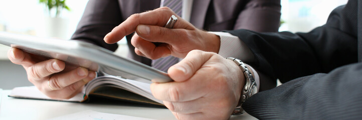 Two businessman are looking and studying statistics on tablet display closeup. Male hand opponent holds pen and points out problem collaboration business coach cooperation partnership palm concept