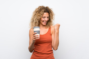 Young blonde woman with curly hair holding a take away coffee celebrating a victory