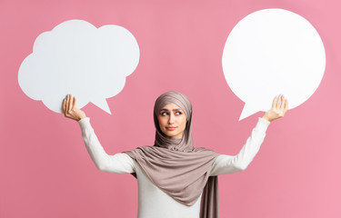 Wall Mural - Two empty speech bubbles in hands of concerned muslim woman