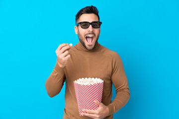 Wall Mural - Young handsome man with 3d glasses and holding a big bucket of popcorns