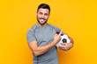 © luismolinero - Man over isolated yellow background with soccer ball and pointing to the lateral