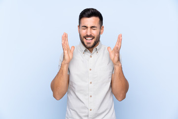 Young handsome man with beard over isolated blue background laughing