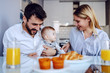 © Dusan Petkovic - Young happy parents sitting in dining room with their adorable baby boy. Man holding baby. On table is breakfast.